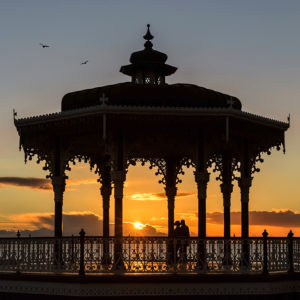 A romantic couple enjoy the sunset on Brightons bandstand