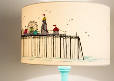 'The Pier' - hand cut, hand guided, machine embroidered lampshade. This design is a fun interpretation of the great British Pier! 2 sizes available 30cm x 21cm high - drum style - medium £105 40cm x 23cm high -drum style - large £115 Lara Sparks - embroidery