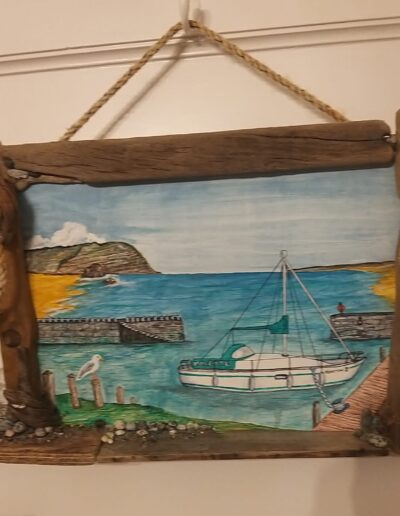 Julie's seascape painting hanging in a wooden frame made by driftwood