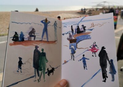 A photograph of Amanda's sketchbook capturing figures along the seafront