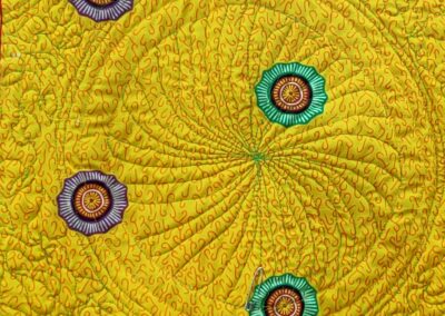 A yellow textile quilt with intricate patterns