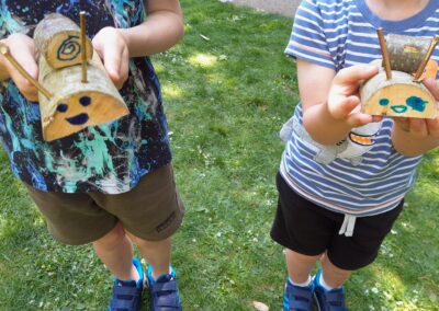 A photograph of two children holding animals they made out of wood