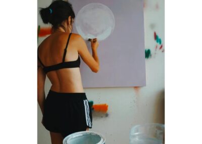 A photograph of Ruby Taylor painting in her studio