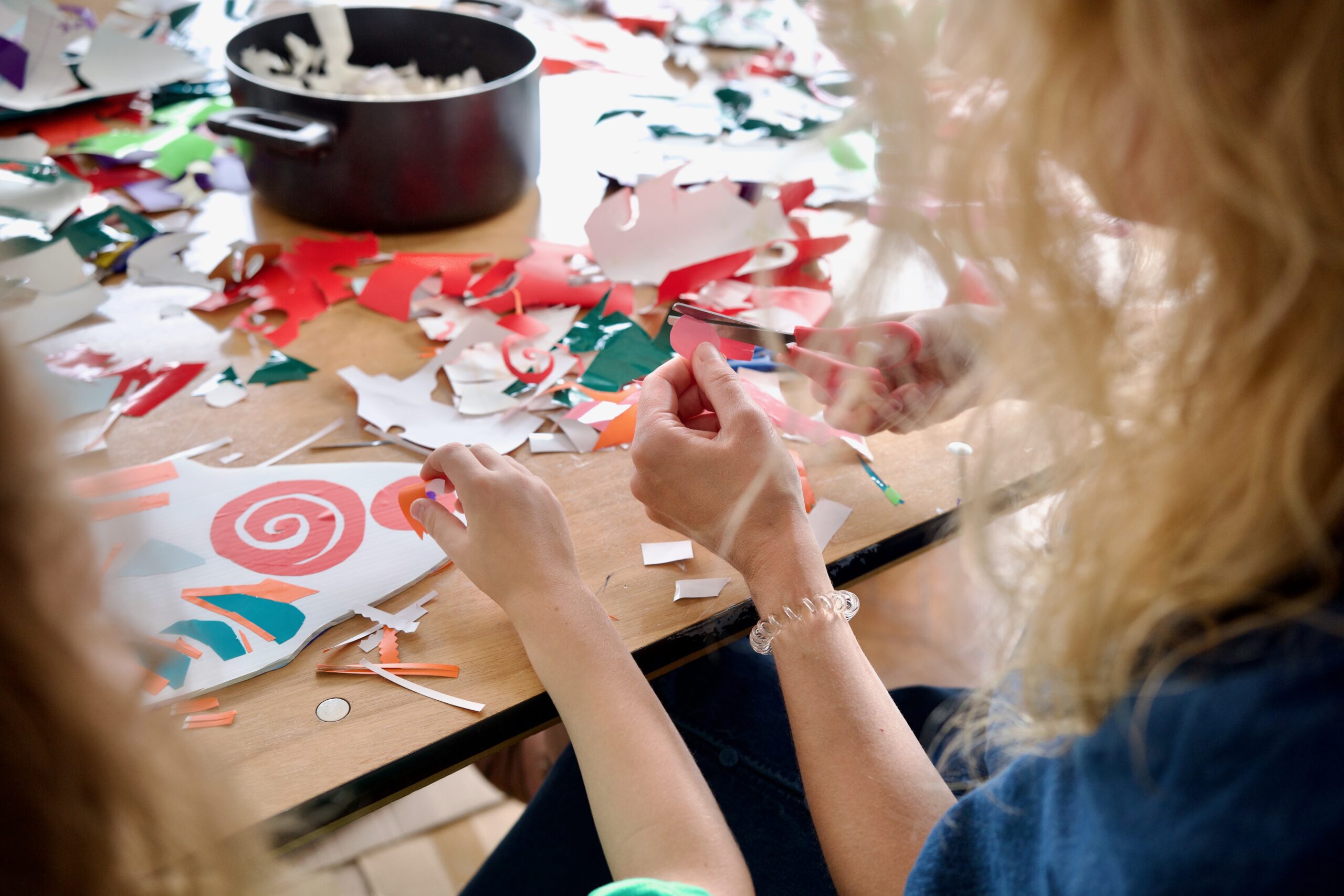 A photograph of two workshop participants cutting some coloured vinyl